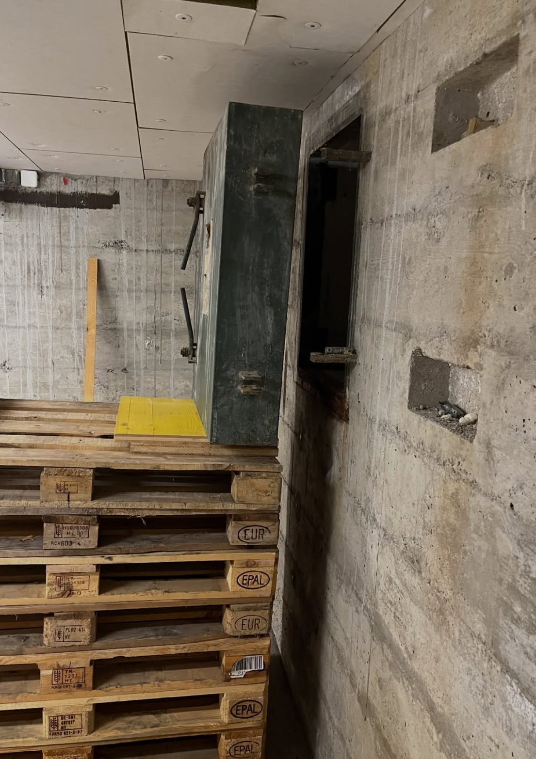 Volet d'abri PC démonté devant la niche ouverte dans le mur